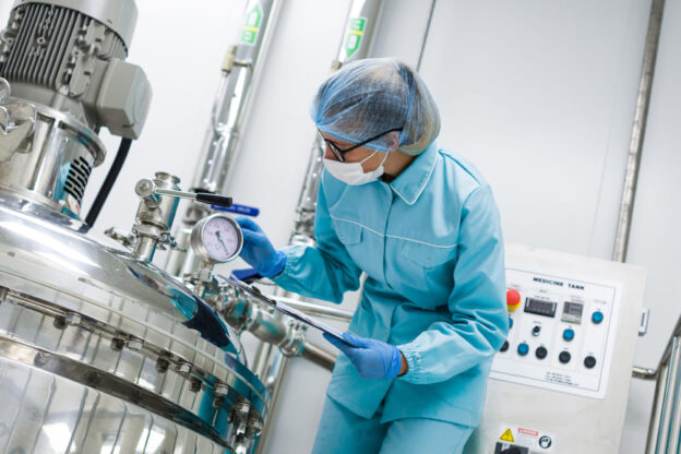 Cientista controlando válvula solenoide em sistema criogênico de laboratório industrial