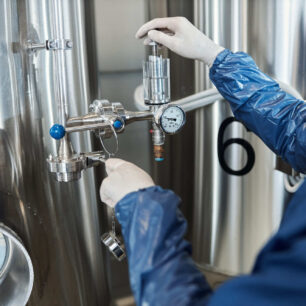 Técnico ajustando válvula solenoide criogênica em sistema industrial de refrigeração com fluido frigorífico