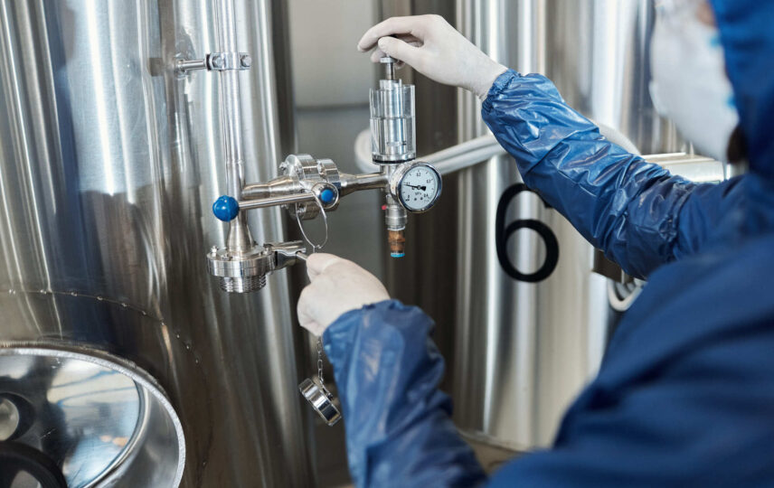 Técnico ajustando válvula solenoide criogênica em sistema industrial de refrigeração com fluido frigorífico